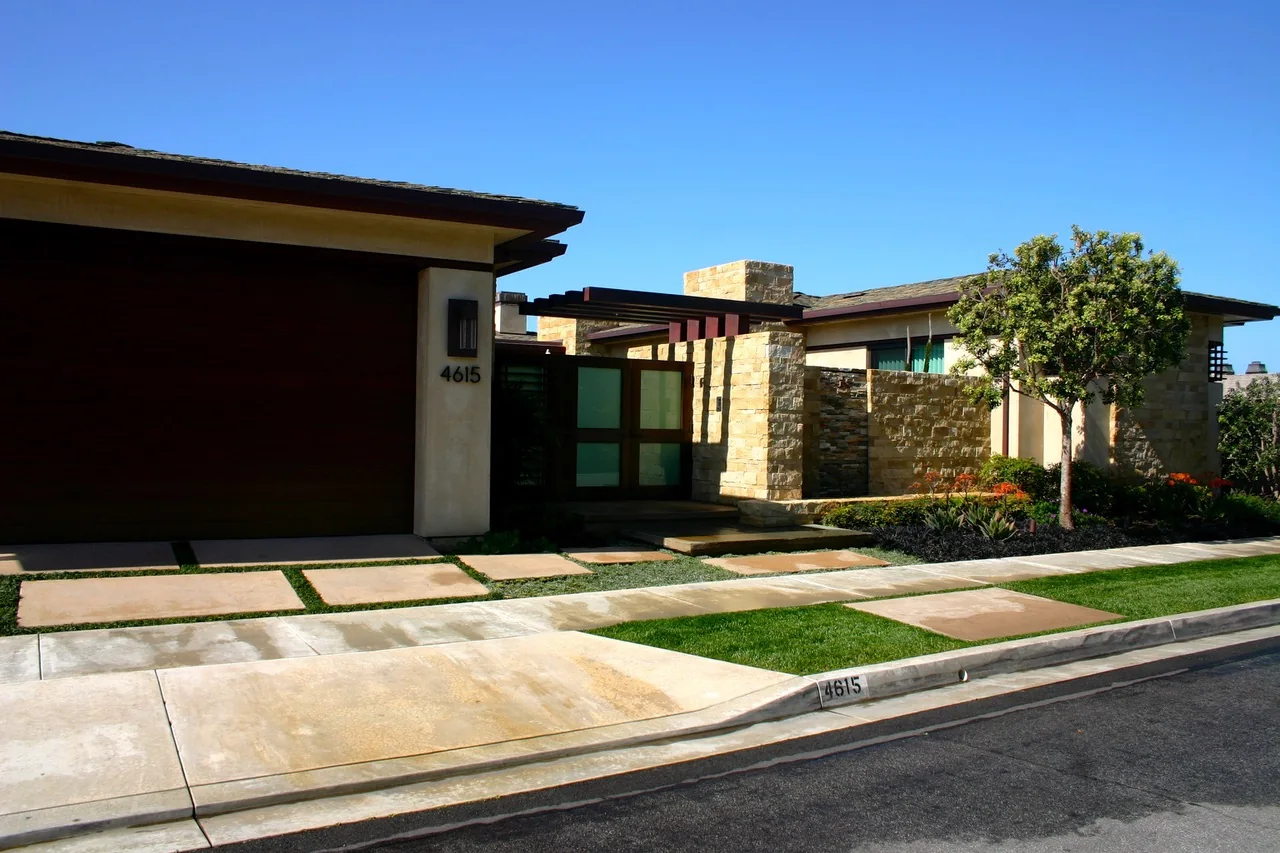 Modern driveway with lawn strips, stone walls, and an entry gate