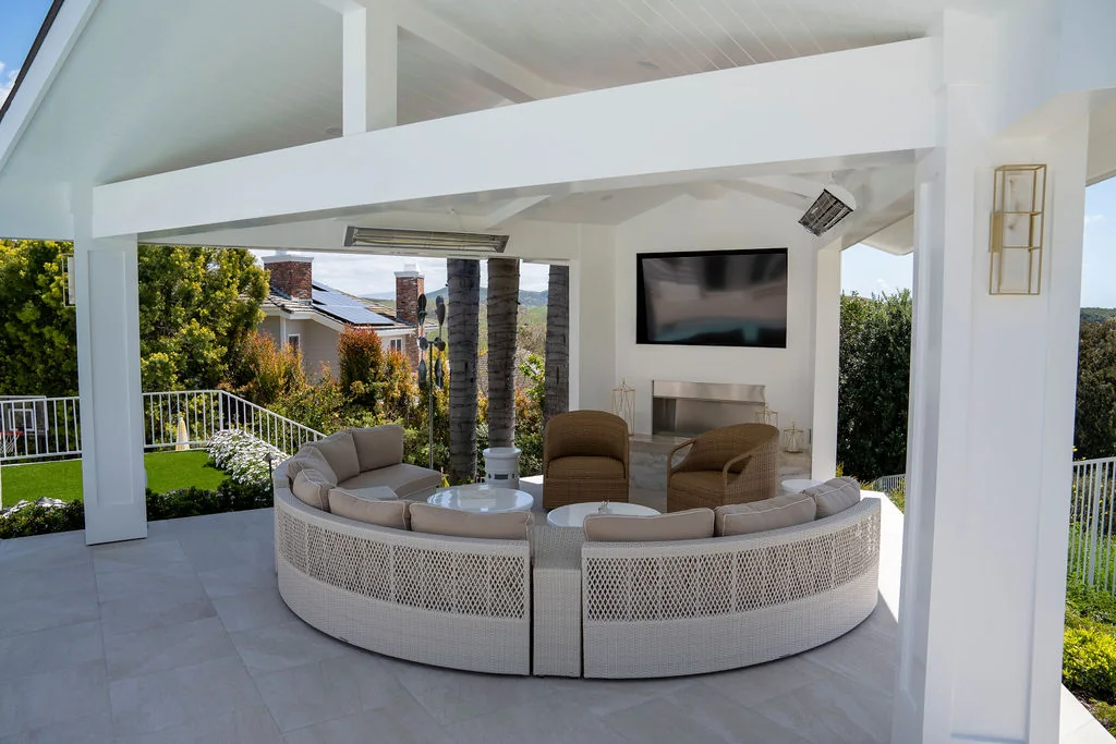 White outdoor pavilion with curved seating and a stone fireplace