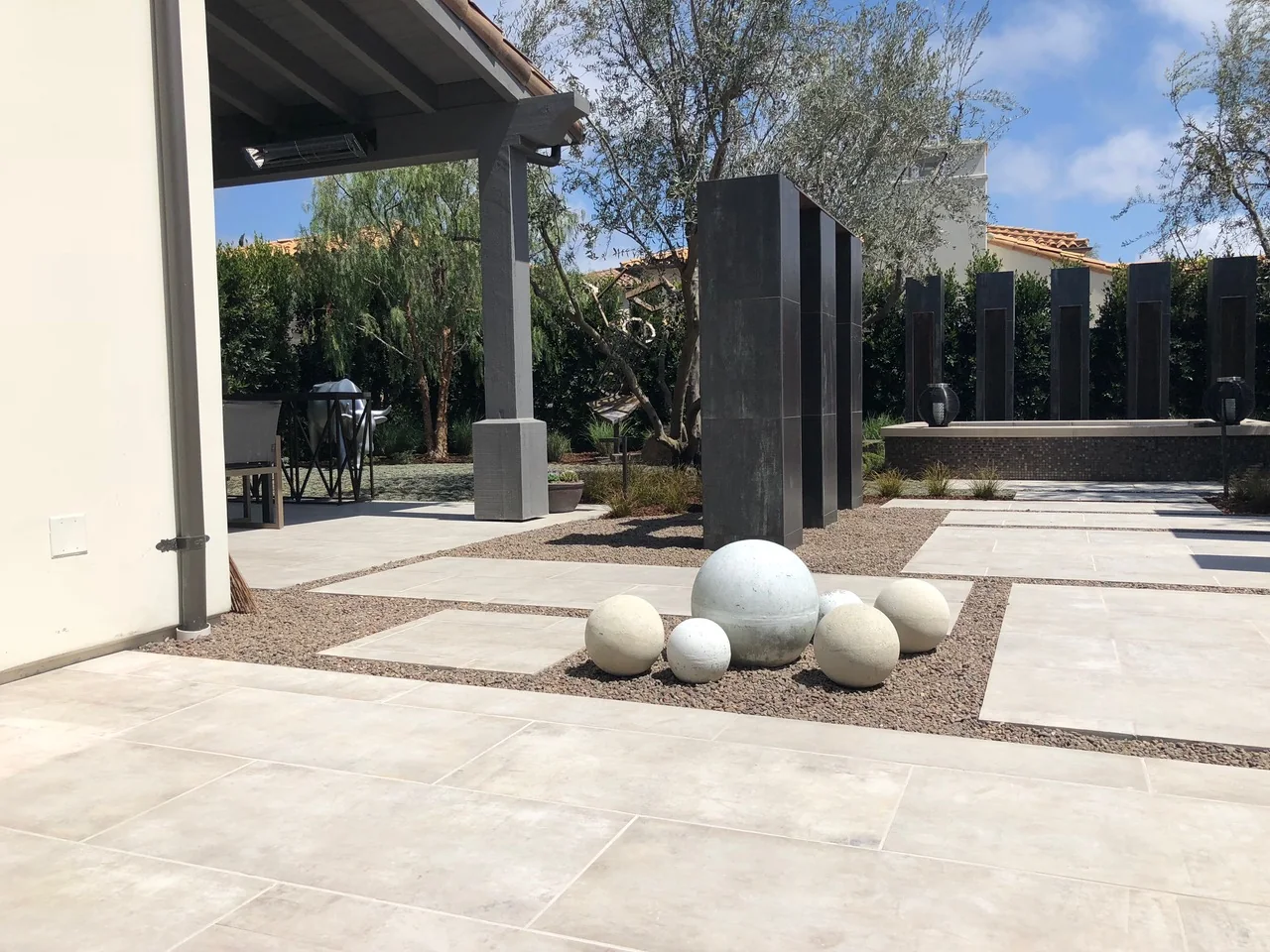 Contemporary paved entrance with a tall vessel and white decorative spheres