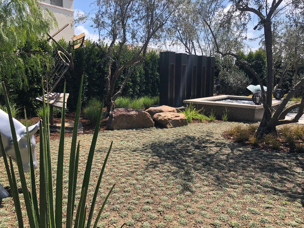 Gravel garden with trees, boulders, and a low water vessel