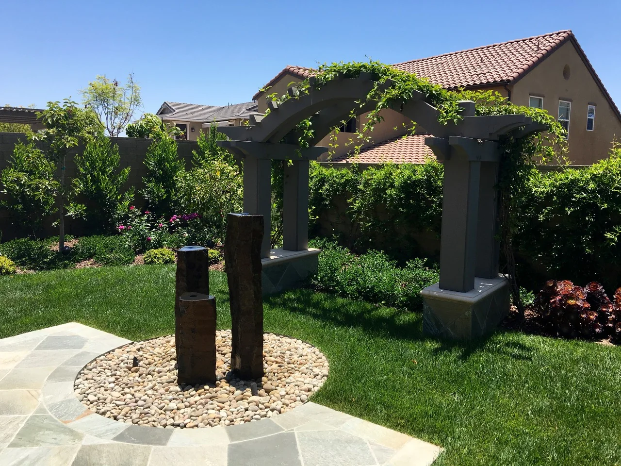 Green garden with timber pergola and tall sculptural accents
