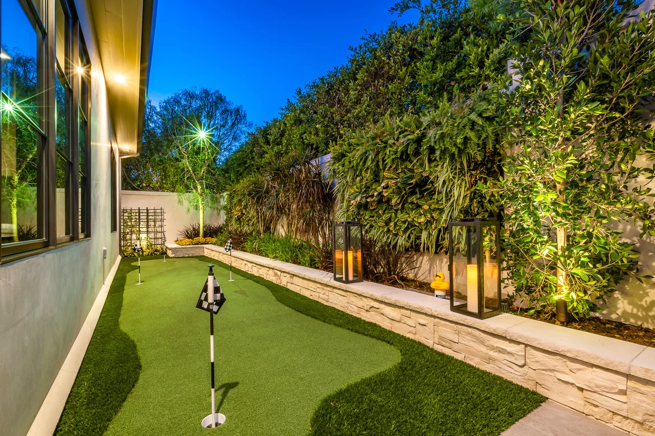 Narrow garden with lawn, bamboo screening, and warm landscape lighting