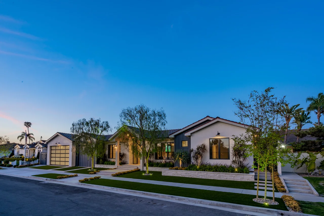 Landscaped front garden with palms beside a single-story home at dusk