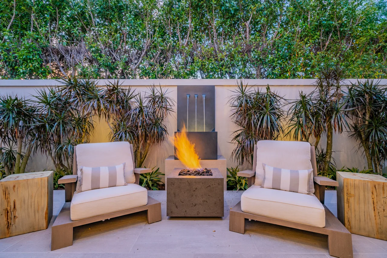 Two armchairs flanking a tall outdoor fire feature