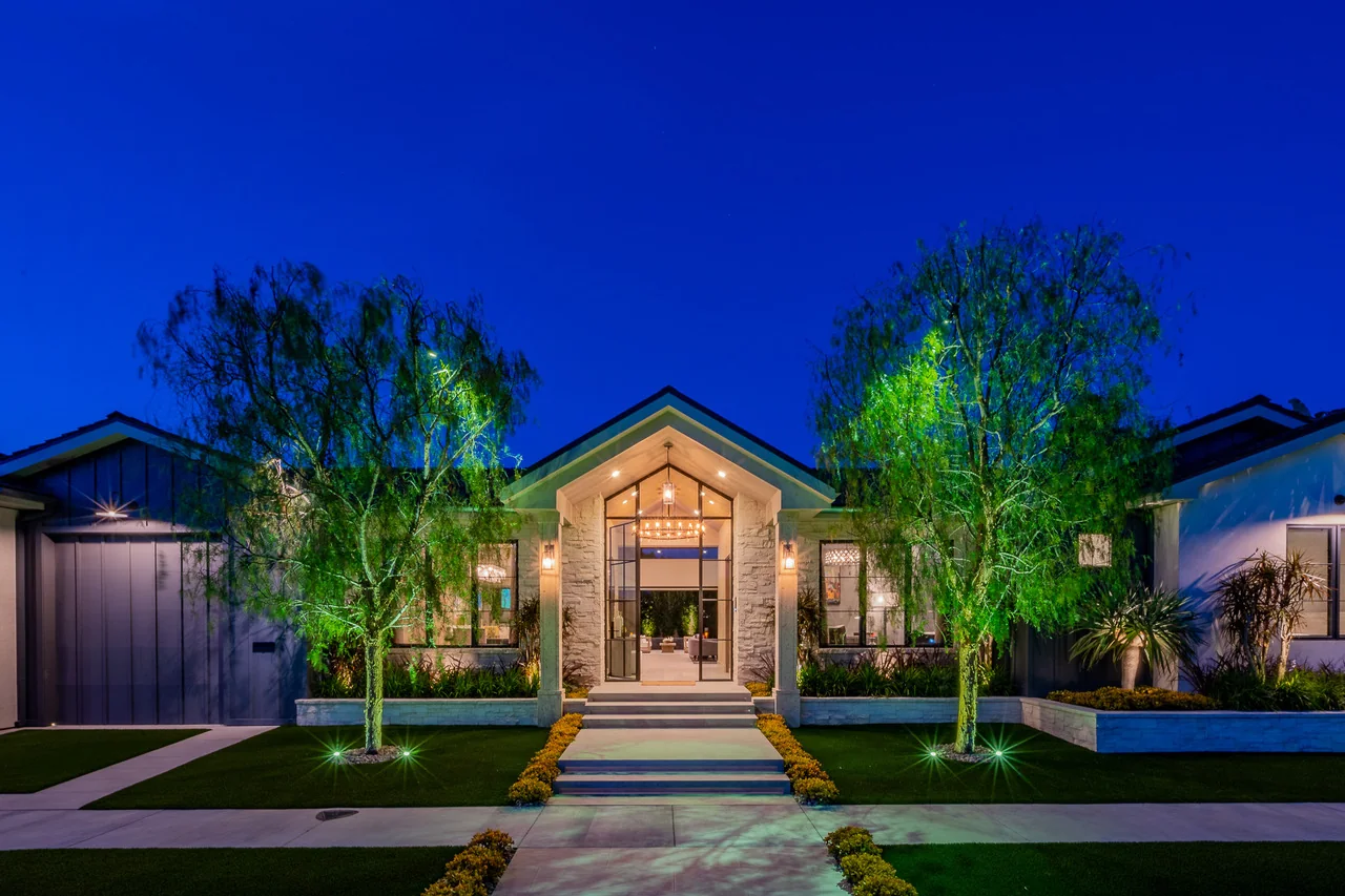 Symmetrical illuminated entry garden leading toward a home at night