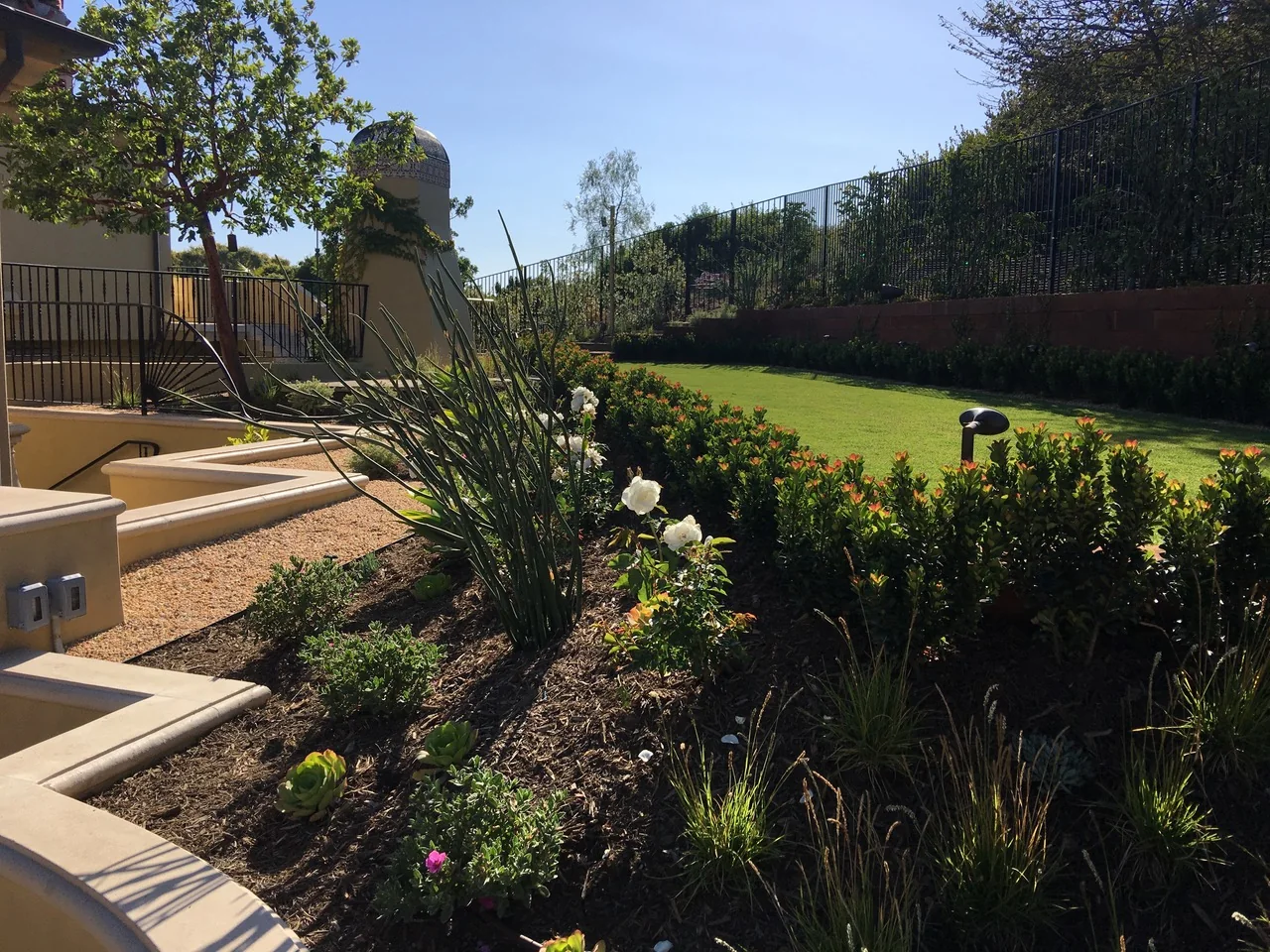 Expansive lawn with planting beds, mature trees, and stone steps