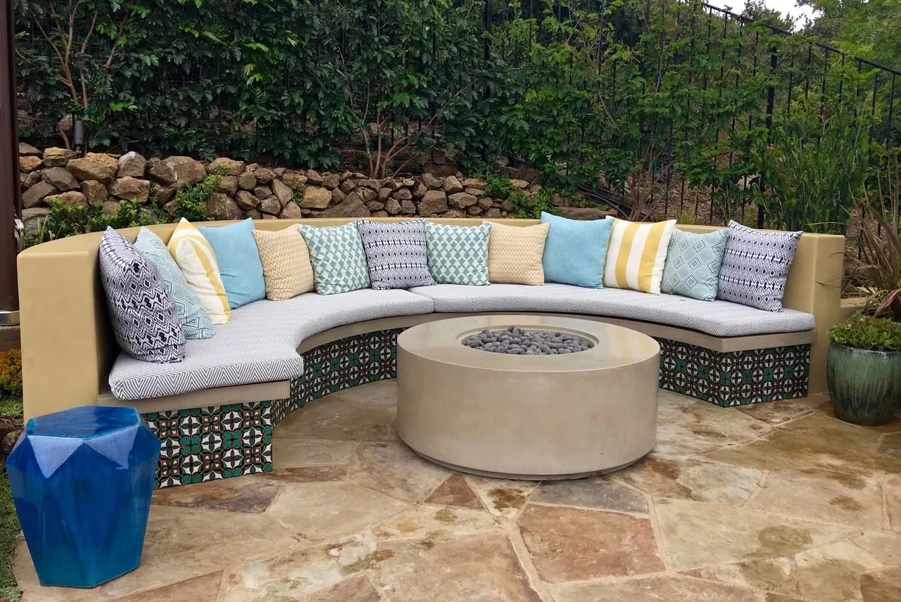 Curved outdoor sofa and round fire feature against layered planting